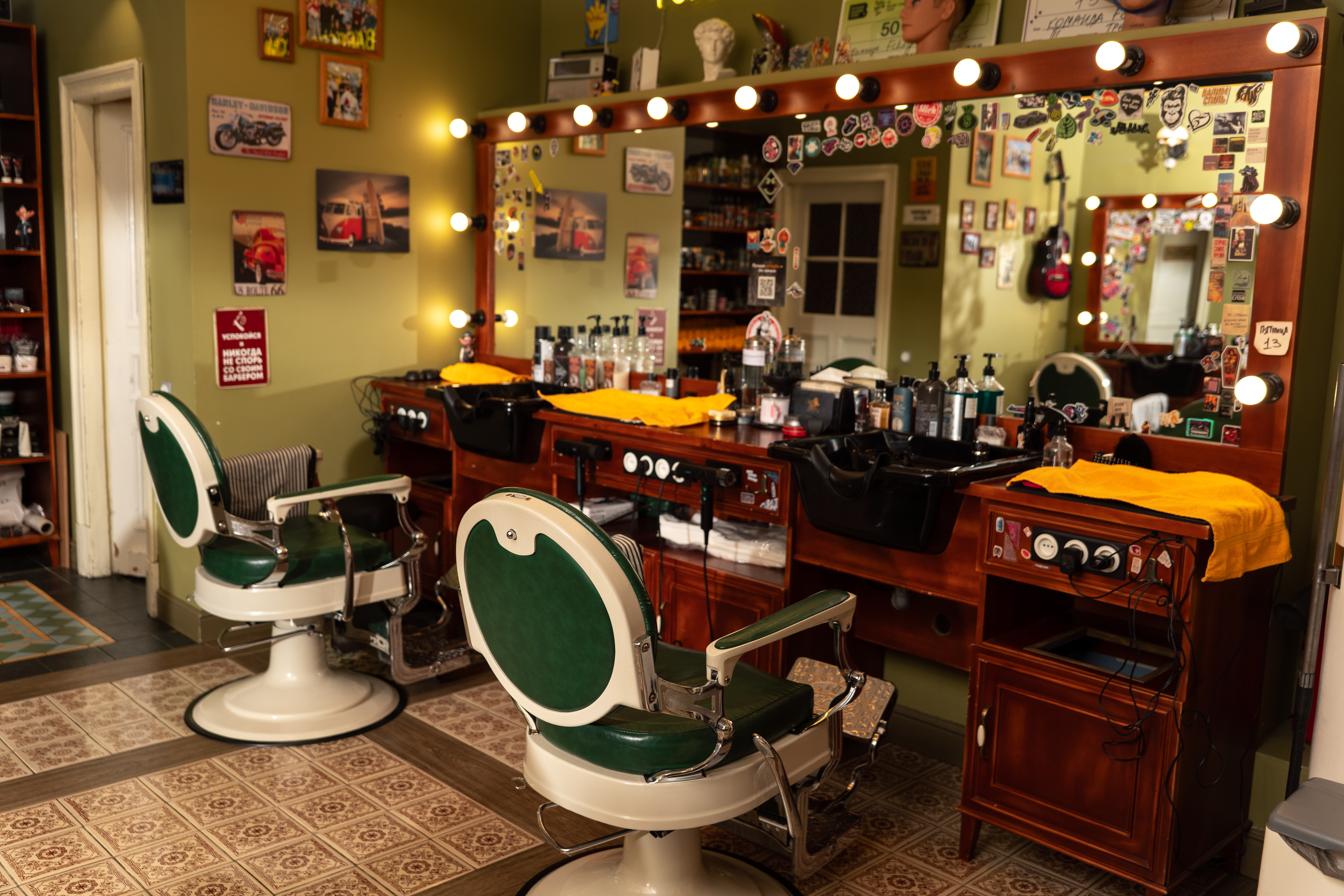 Интерьер барбершопа Fckng Barbers Полянка с двумя креслами напротив рабочей зоны из красного дерева с большим зеркалом
